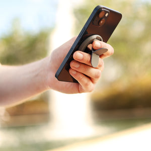 Man holds black phone with grey grip outside