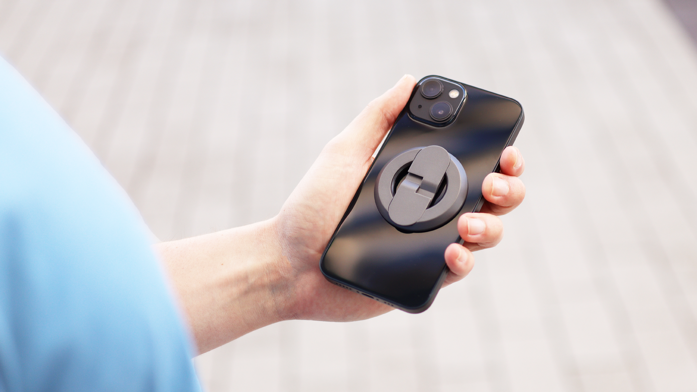 A man holds a black phone with a grey grip outside